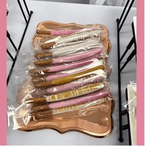 A tray of decorated pretzel sticks in various colors and designs, wrapped in clear plastic.